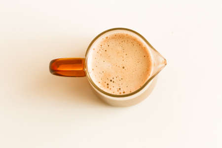 Fresh coffee drink, cappuccino with foam on a neutral background in a glass mugの写真素材