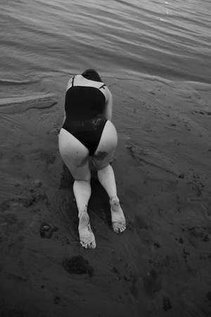 a dancer moves freely on the beach, art shooting of a dancer on black and white film. A woman in a black bodysuit on the beachの写真素材