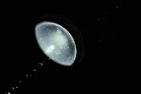 Glass beads illuminated by a cold flashlight, silver light and glass background , abstraction and...