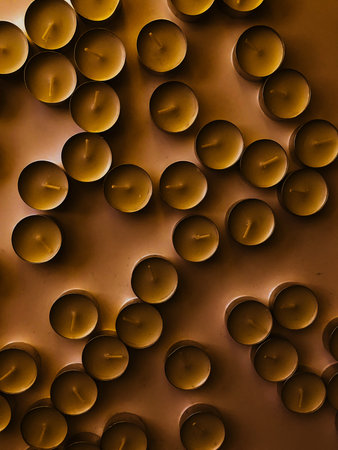 A set of candles in close-up, a background of tea candles. Blurred images, light noises and...