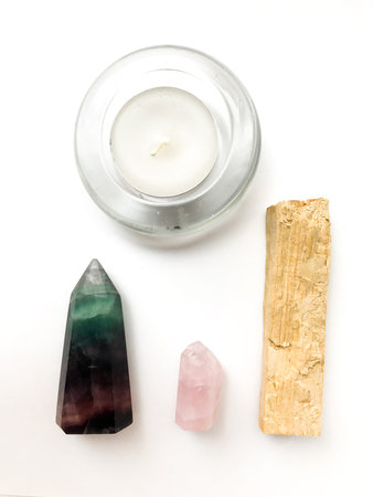 Palo santo incense stick for meditation, candle and rose quartz crystal on a white background, place...