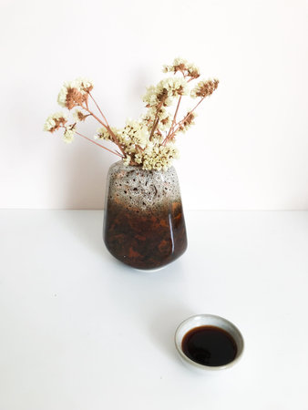 Beautiful tea background, ceramic mug with dark Chinese tea of the Shu Puer variety surrounded by dried flowers lemon staticeの写真素材