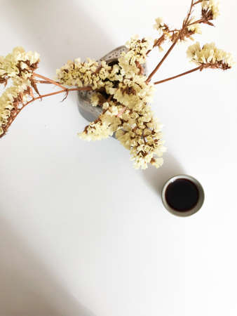 Beautiful tea background, ceramic mug with dark Chinese tea of the Shu Puer variety surrounded by dried flowers lemon staticeの写真素材