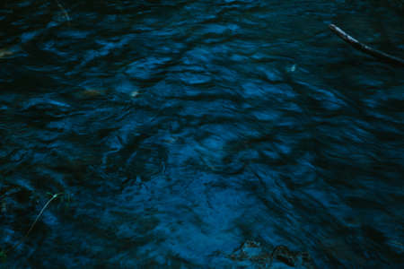 Blue water in the mountain river. Abstract background of dark blue water.の写真素材