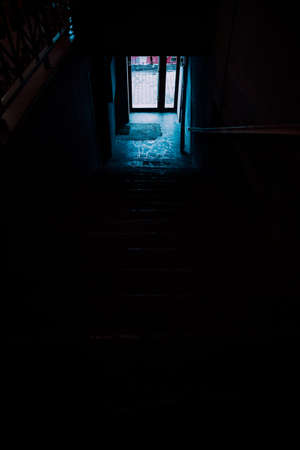 A dark corridor in a dark room with a light coming through the windowの写真素材