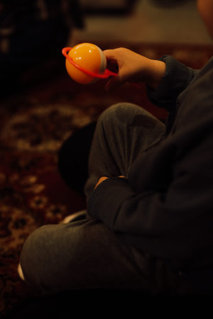 A boy sits on the floor and holds a cup of tea.