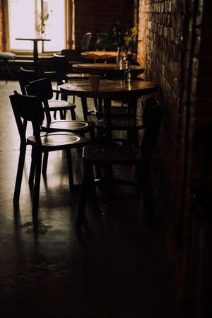 Interior of a cafe with wooden tables and chairs in the darkの写真素材