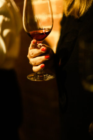 Close-up of a woman's hand holding a glass of red wine