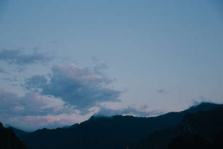Silhouette of mountains in the evening. Beautiful sky with clouds.の写真素材