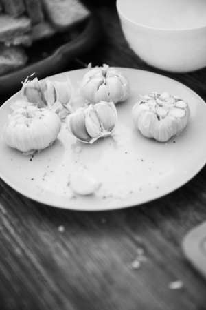 Garlic on a white plate on a wooden table. Black and white photo.の写真素材