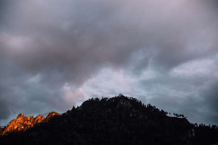 Dramatic sky with dark clouds and silhouette of a mountain peakの写真素材
