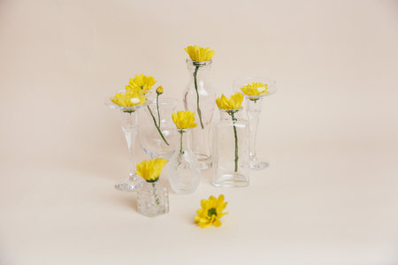 Stylish art background, yellow flowers in glass vases on a beige background. Blur and long shutter speed, the effect of whirling and moving the cameraの写真素材