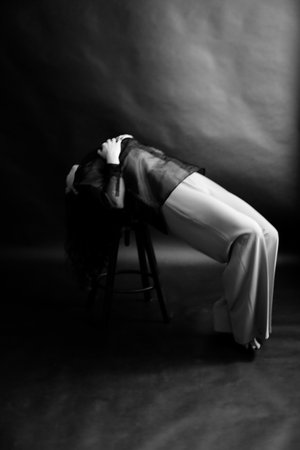 Black and white photo of a beautiful young woman lying on a chairの写真素材