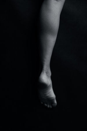 Feet of a young girl on a black background. Black and white photoの写真素材