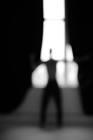 Blurred silhouette of a man standing in front of the window.の写真素材
