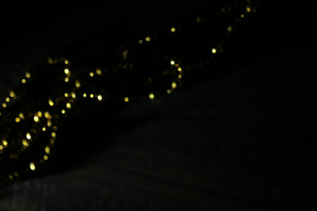 Golden Christmas garland on a black background. Blurred background.の写真素材
