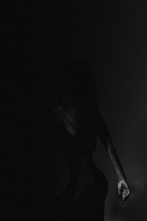 Silhouette of a girl in a black dress on a dark backgroundの写真素材