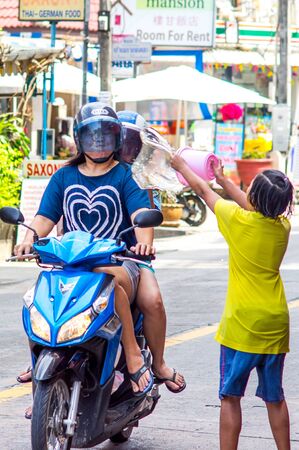 Patong, Phuket, Thailand - 04/13/2014. Songkran Festival Asian girl drenches a bike with people passing by herのeditorial素材