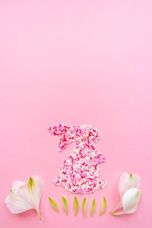 Easter funny bunny from topping. Decorative eggs with flower petals. Flat lay on a pink background. Screensaverの写真素材
