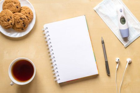 Top view on a wooden table. Work, study at home during quarantine. Workspace with a cup of tea,...