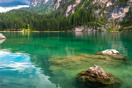 The magical lake of Braies. Emerald body of water reflects the surrounding forest and mountains....