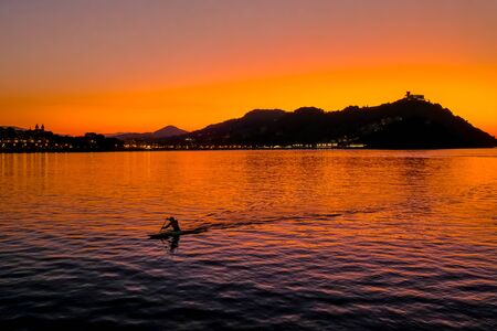 Sunset on Mount Igueldo and and man with a paddle in koyak in Donosti San Sebastian, Basque Country, northern spain.の写真素材
