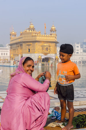 Amritsar, India - November 21, 2011: The Sikh family of pilgrims, mother and son, dresses up a...