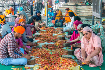 Amritsar, India - November 21, 2011: Unknown Indian people peel vegetables for a free meal for pilgrims. Golden Temple in Amritsar, Punjab, India.のeditorial素材