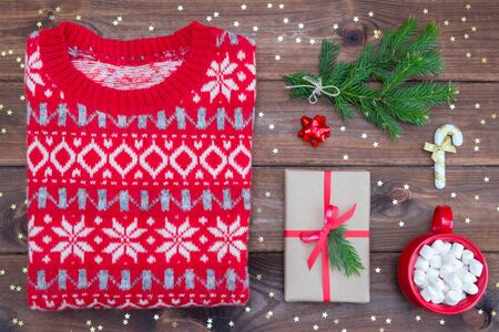 Top view christmas sweater, mittens, gift and coffee with marshmallows and decorations on a green background. Flat lay.の写真素材