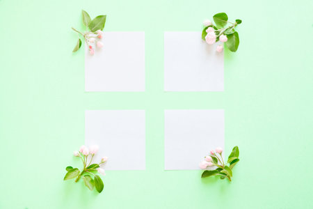 Summer and spring composition. four flowering branches of apple trees, white paper blank on mint...