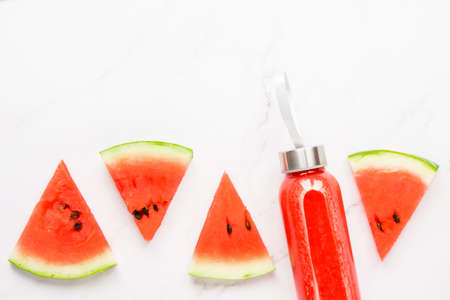 Fitness, healthy nutrition diet concept. Fresh cool watermelon juice in a glass jar and watermelon slices on a light background. Summer concept. copy space top view flat lay.の写真素材