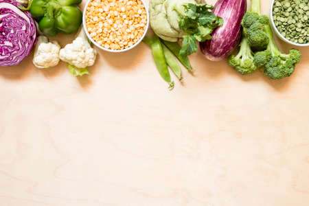 Top view set raw of green, red and purple vegetables and protein for vegetarians spread on wooden background. Copy spaceの写真素材