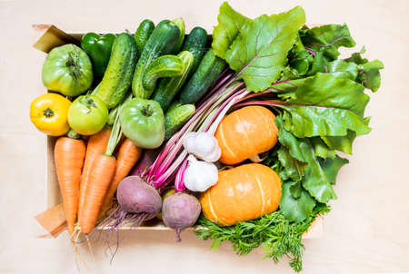 Top view fresh organic vegetables in eco friendly wooden box on wooden background. flat layの写真素材