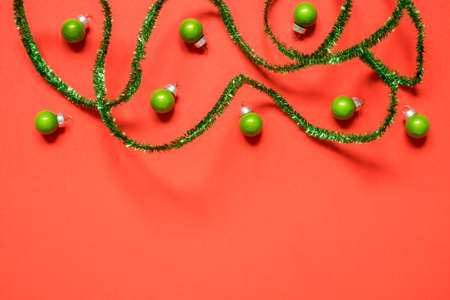 New Year or Christmas composition 2021. Top view xmas decorative red paper background with green tinsel and Christmas decorations wiht copy space. Mockup greeting card. Flat layの写真素材