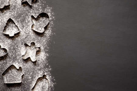 Christmas cookies molds and flour on black background with copy space.の写真素材