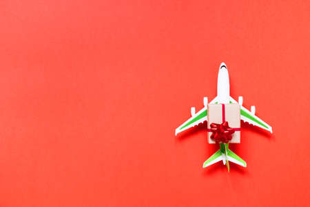 Airplane with christmas gift on red background with copy spaceの写真素材