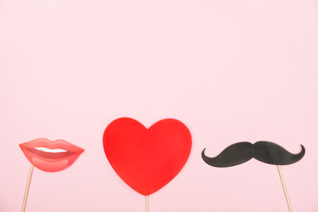 Valentine's day, love, romantic concept. Red heart, mustaches and lips paper prop on pink background. Greeting card. Flat lay, top view, copy space.の写真素材