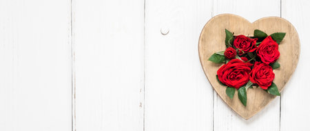 Valentine's day, love, romantic concept. Red roses and wooden heart on white background. Flat lay, top view, copy space. Banner.の写真素材