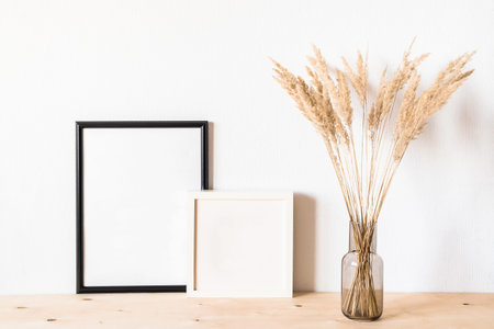 Dried flowers and a photoframes against a light wall in a minimalist style