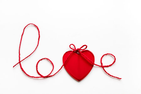 Valentine's day concept. Red heart and word love made from woolen rope on white background with copy...