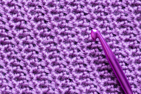 Handmade close-up simple lilac crochet pattern with crochet hook.