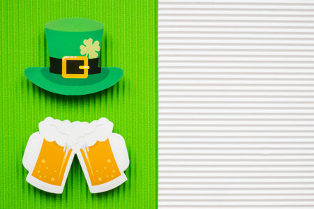 St Patricks Day hat and beer on green and orange background with copy space.
