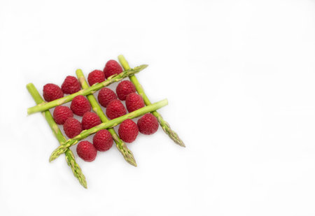 Green asparagus and red raspberries isolated on a white backgroundの写真素材