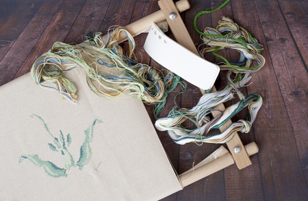 Embroidery canvas on a wooden frame with treads on a wooden backgroundの写真素材