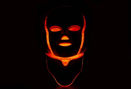 Led mask with neck glowing red on black backgroundの写真素材