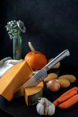 Colorful autumn vegetables for pumkin soup and a knife on black background, copy spaceの写真素材