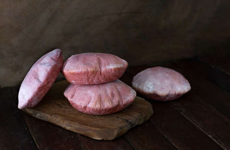Four pink backad pita breads on wooden cutting board on dark backgroundの写真素材