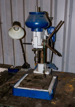 Old bench drill press in metal workshop, vintage industrial machinery