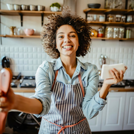 Young woman having a good day, taking a selfie in the kitchenの素材