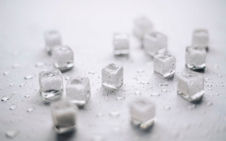 Ice cubes with water drops scattered under natural light on a white backgroundの素材